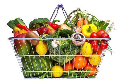 Photo of a wire shopping basket full of fresh fruit and vegetables, isolated on a white background.